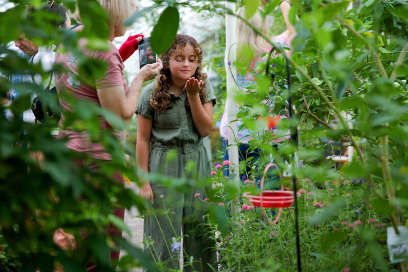A young girl admires a butterfly in her hand as her mother takes a photo at the Erie County Botanical Gardens in Buffalo.